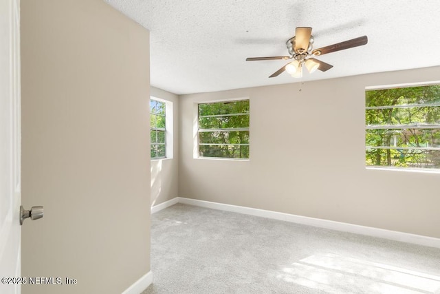 empty room featuring a ceiling fan, baseboards, light carpet, and a textured ceiling