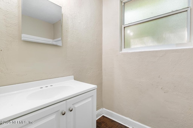 bathroom featuring vanity, a textured wall, baseboards, and wood finished floors