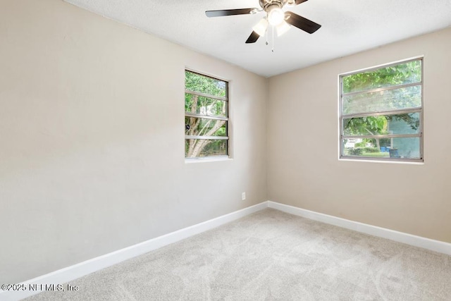 spare room with a ceiling fan, baseboards, and light colored carpet