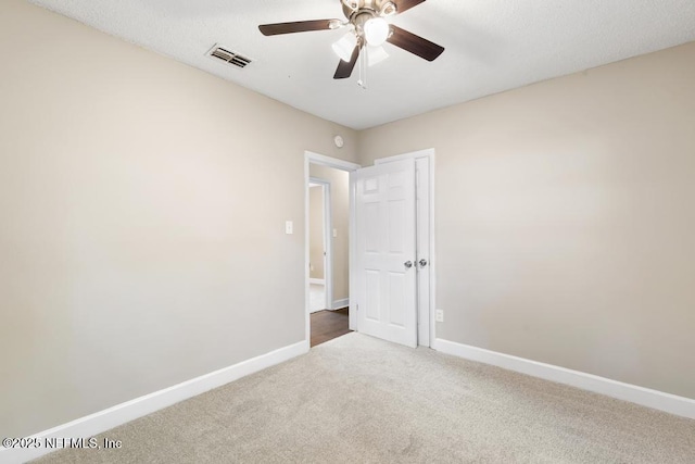 carpeted empty room with baseboards, visible vents, and ceiling fan