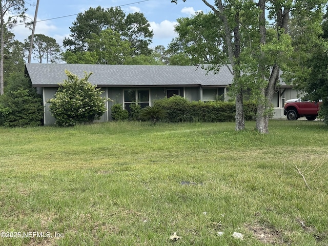 ranch-style home with a shingled roof and a front lawn
