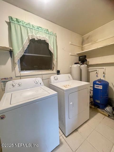 clothes washing area with washing machine and dryer and light tile patterned floors