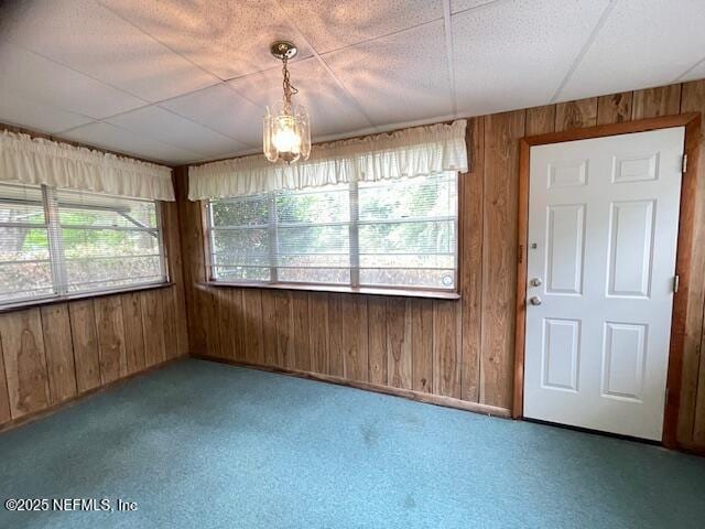 unfurnished dining area featuring wood walls, carpet floors, and baseboards