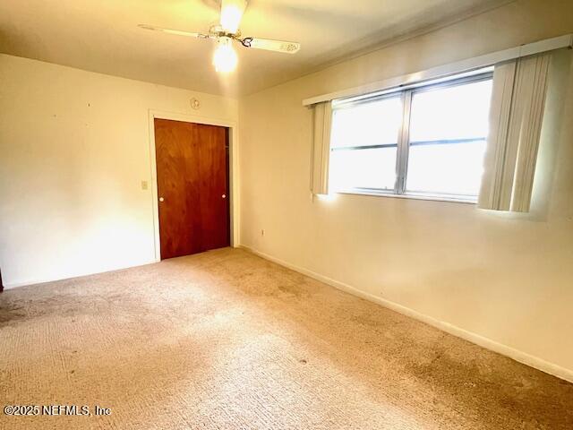 carpeted empty room with baseboards and a ceiling fan