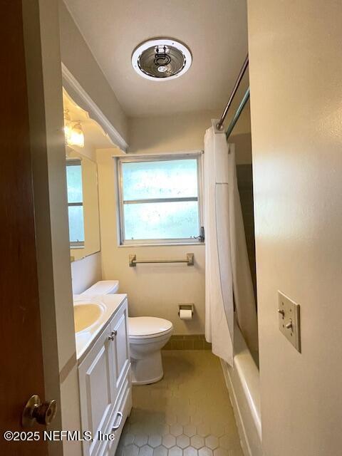 full bath featuring vanity, toilet, tile patterned flooring, and shower / bath combo with shower curtain