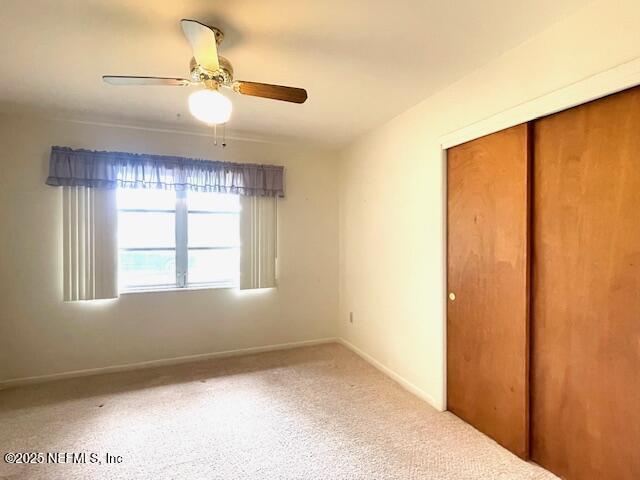unfurnished bedroom with a closet, baseboards, a ceiling fan, and carpet flooring