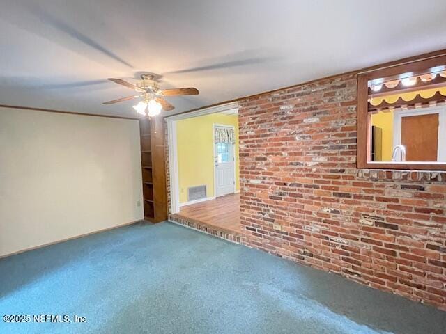 empty room featuring carpet floors, ceiling fan, and brick wall