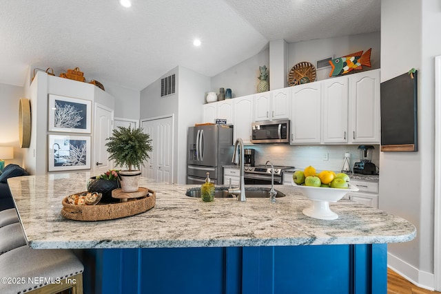 1421 Kipling Ln, Ponte Vedra, FL 32081 - kitchen with appliances with stainless steel finishes, vaulted ceiling, a breakfast bar area, decorative backsplash, and white cabinetry