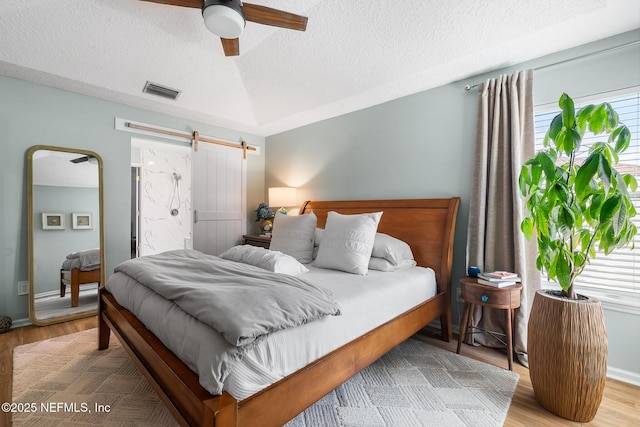 1421 Kipling Ln, Ponte Vedra, FL 32081 - bedroom with a textured ceiling, a barn door, wood finished floors, baseboards, and ceiling fan
