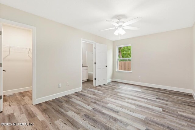 2911 Wilcox St, Jacksonville, FL 32209 - unfurnished bedroom with a walk in closet, baseboards, a closet, light wood finished floors, and connected bathroom