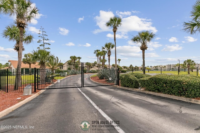 view of road with a gated entry, a gate, and curbs