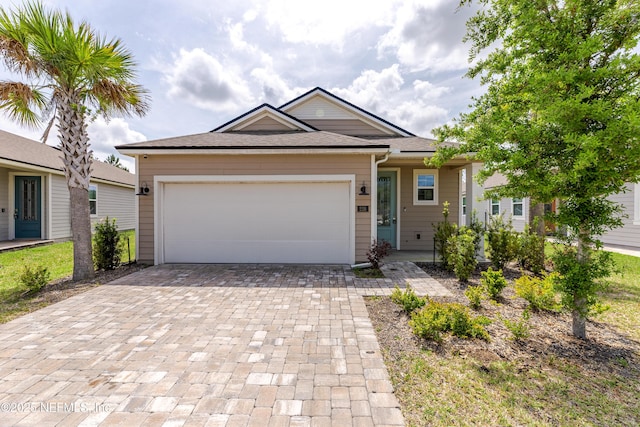 ranch-style house with a shingled roof, an attached garage, and decorative driveway