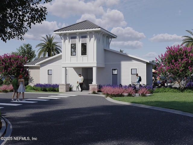 modern farmhouse featuring a standing seam roof, fence, board and batten siding, and metal roof