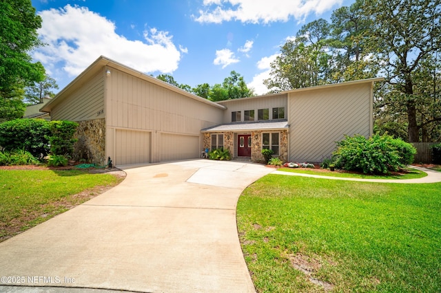 mid-century home featuring a garage, a front yard, driveway, and stone siding