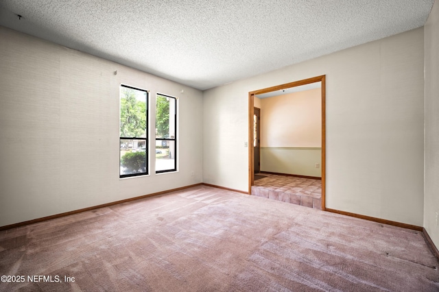 carpeted spare room with baseboards and a textured ceiling