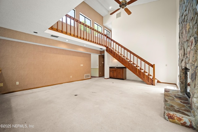 unfurnished living room featuring baseboards, visible vents, and stairway