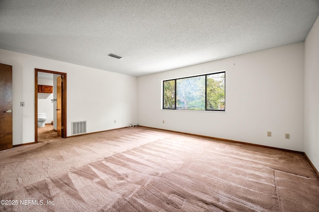 unfurnished room featuring baseboards, carpet flooring, a textured ceiling, and visible vents