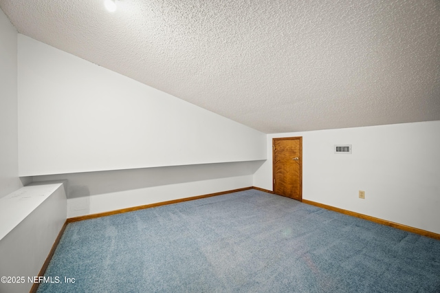 bonus room with baseboards, carpet flooring, a textured ceiling, and visible vents