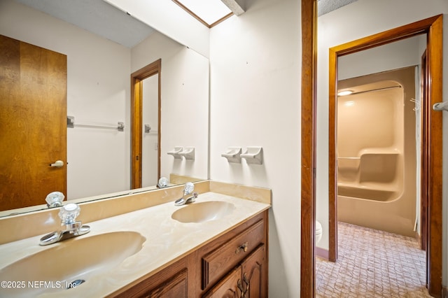 bathroom with double vanity, a sink, and toilet