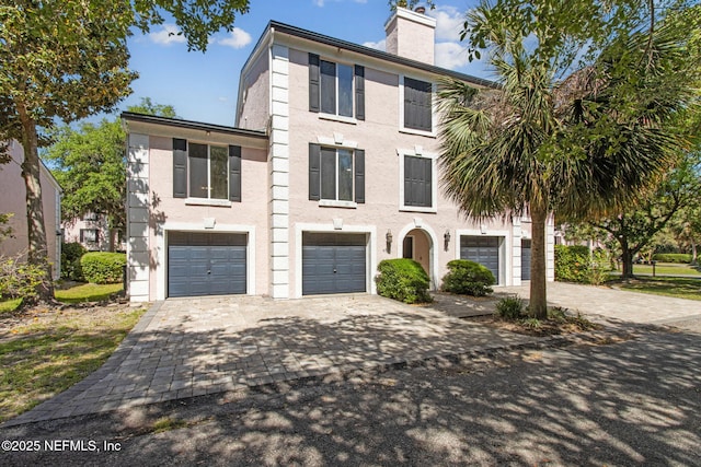 4746 Gulfstream Ct, Fernandina Beach, FL 32034 - view of front facade featuring stucco siding, an attached garage, a chimney, and decorative driveway