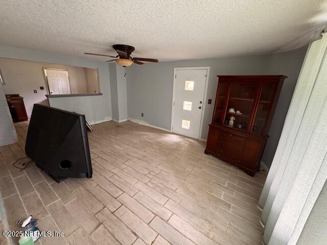 unfurnished living room featuring a textured ceiling and ceiling fan