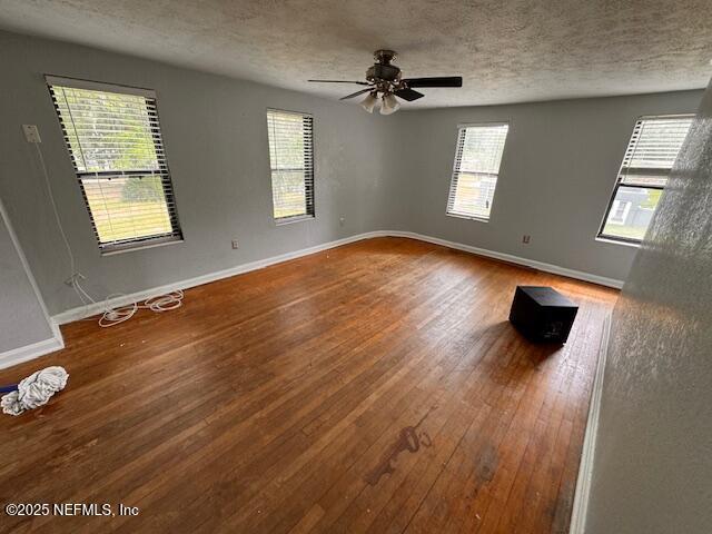 spare room with a ceiling fan, a textured ceiling, baseboards, and hardwood / wood-style floors