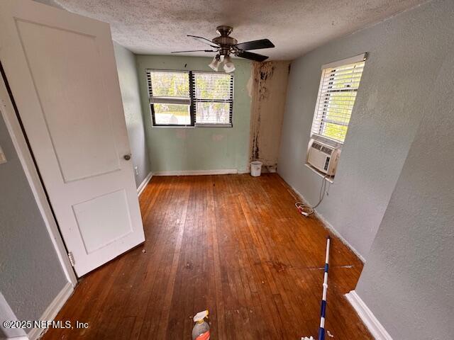 unfurnished room featuring wood-type flooring, a textured ceiling, a wealth of natural light, and ceiling fan