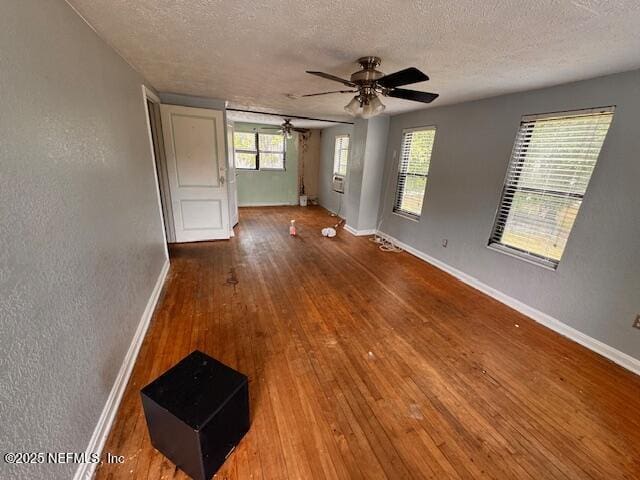 spare room with a textured ceiling, baseboards, a textured wall, and ceiling fan