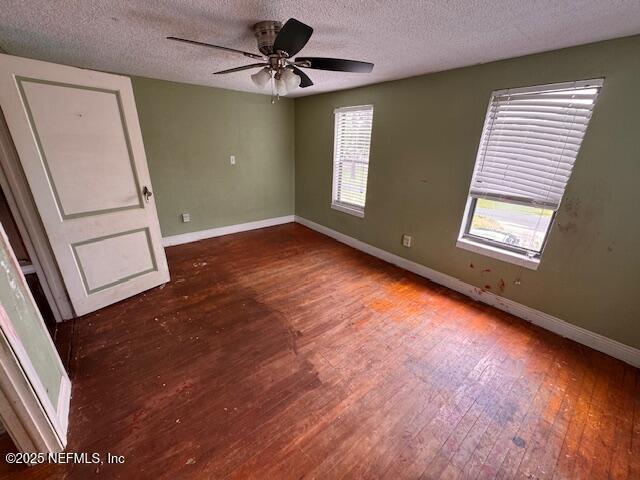 empty room with a textured ceiling, baseboards, ceiling fan, and wood finished floors