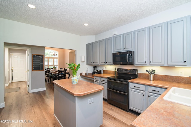 kitchen featuring a kitchen island, double oven range, a textured ceiling, a chandelier, and light wood-style floors