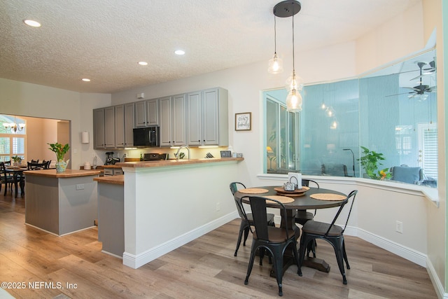 kitchen featuring black microwave, light wood-type flooring, recessed lighting, a sink, and wood counters