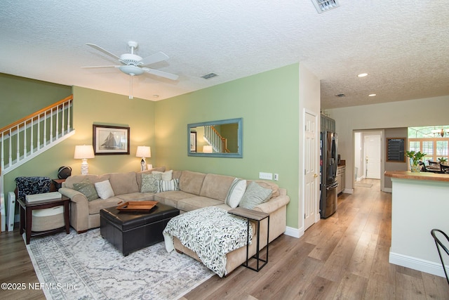 living area with light wood finished floors, a textured ceiling, and visible vents