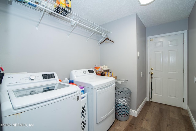 laundry area with washer and dryer, laundry area, a textured ceiling, baseboards, and wood finished floors