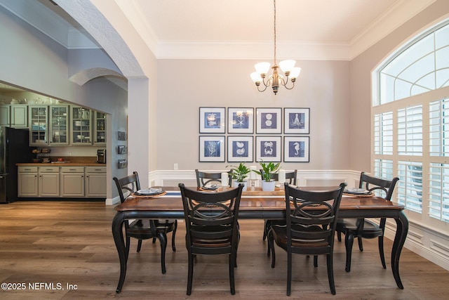 dining room with crown molding, an inviting chandelier, and wood finished floors