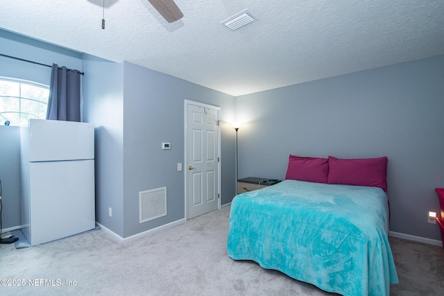 bedroom featuring freestanding refrigerator, visible vents, and carpet floors