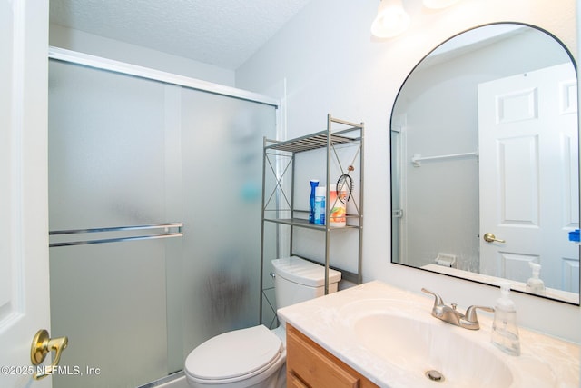 bathroom featuring vanity, toilet, a textured ceiling, and a stall shower