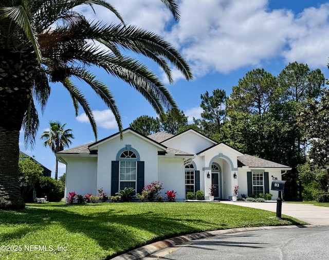 ranch-style home featuring a shingled roof, stucco siding, concrete driveway, and a front lawn