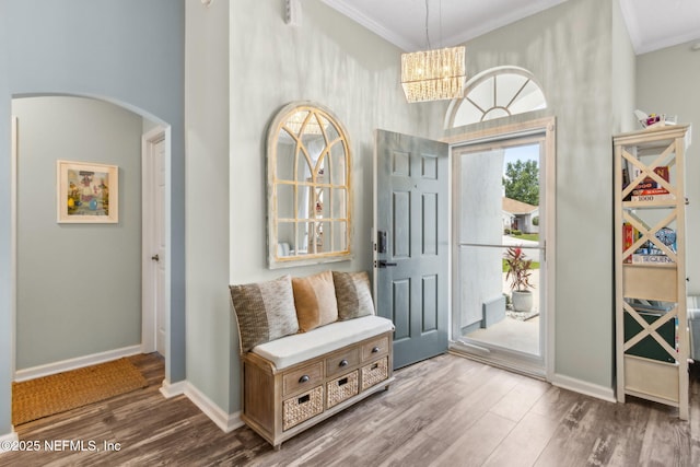 interior space featuring crown molding, arched walkways, baseboards, and wood finished floors