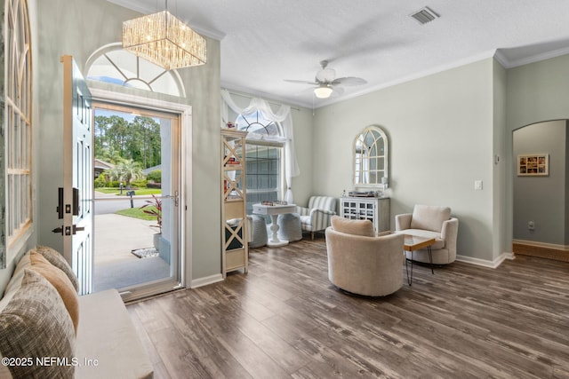 foyer entrance with ornamental molding, wood finished floors, and visible vents