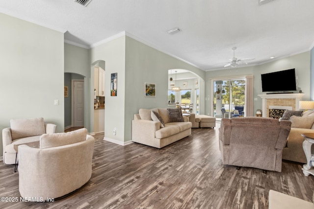 living area with dark wood-type flooring, arched walkways, a ceiling fan, and crown molding
