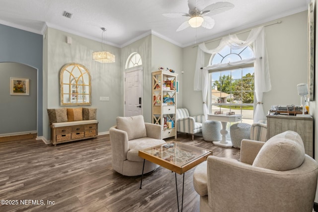 living area featuring visible vents, a ceiling fan, wood finished floors, and ornamental molding