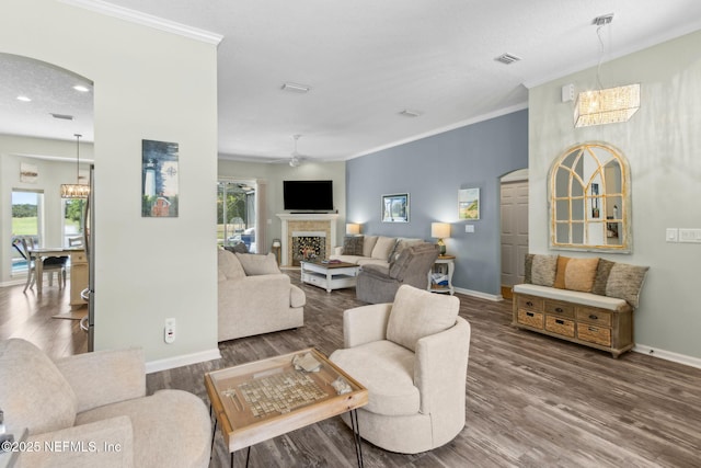 living area with baseboards, arched walkways, wood finished floors, and ornamental molding