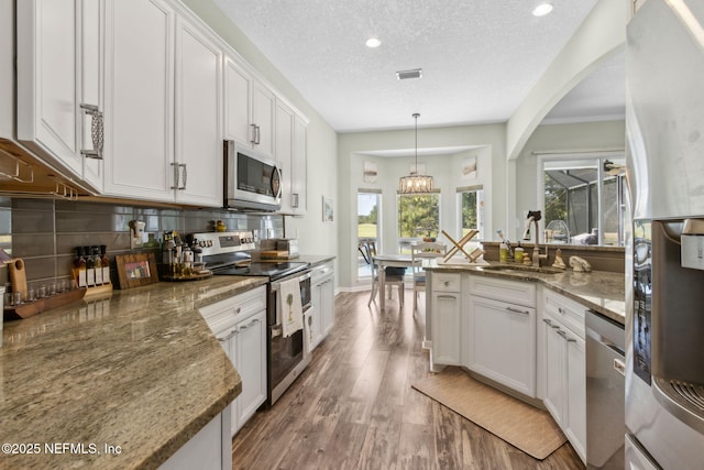 kitchen featuring light wood-style floors, white cabinetry, tasteful backsplash, a sink, and stainless steel appliances