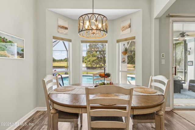 dining area featuring baseboards, ceiling fan with notable chandelier, and wood finished floors