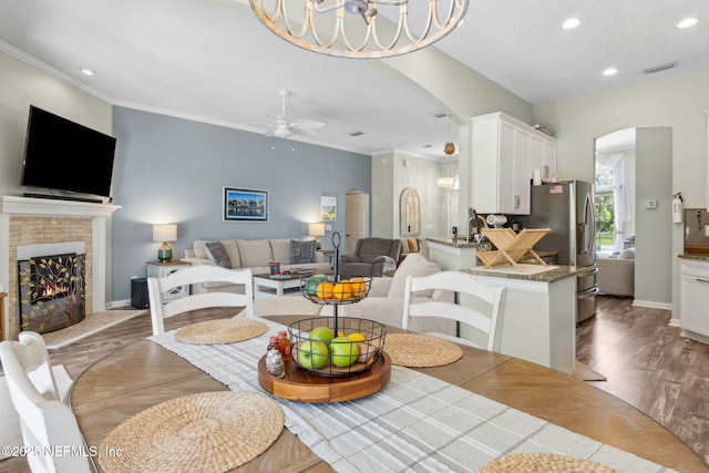 dining room with visible vents, a ceiling fan, wood finished floors, recessed lighting, and arched walkways