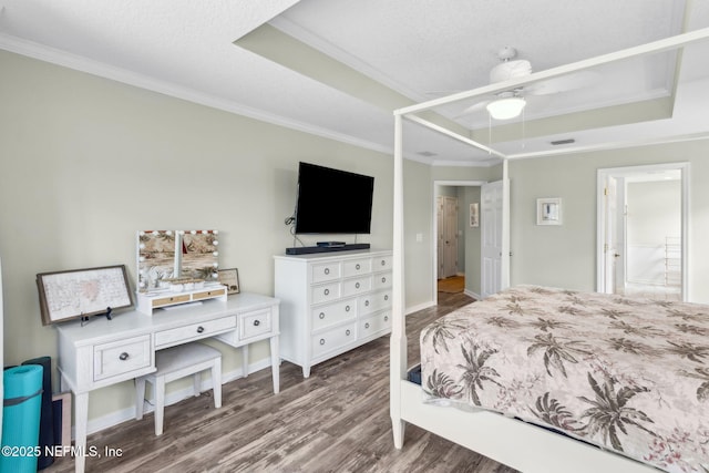 bedroom with ornamental molding, a tray ceiling, wood finished floors, and visible vents