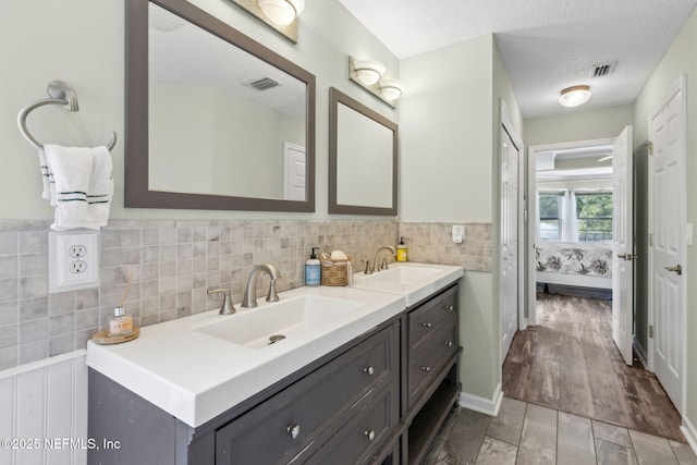full bathroom with visible vents, a sink, ensuite bath, and double vanity