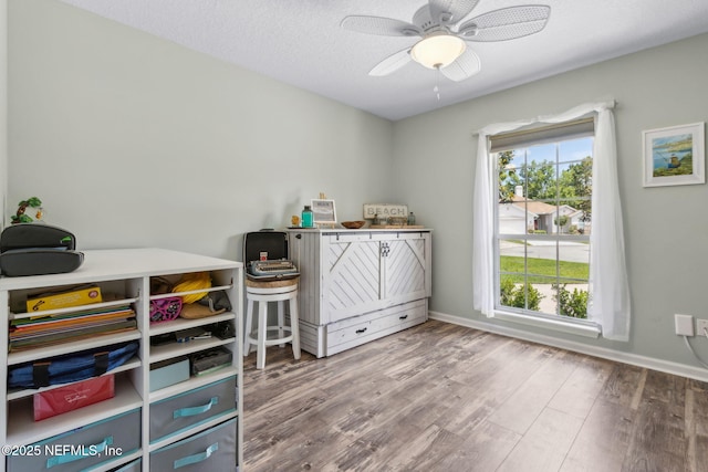 interior space featuring a ceiling fan, baseboards, and wood finished floors