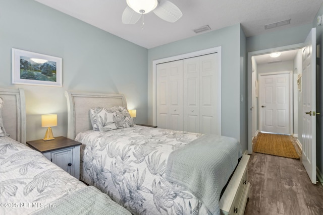 bedroom featuring ceiling fan, a closet, wood finished floors, and visible vents