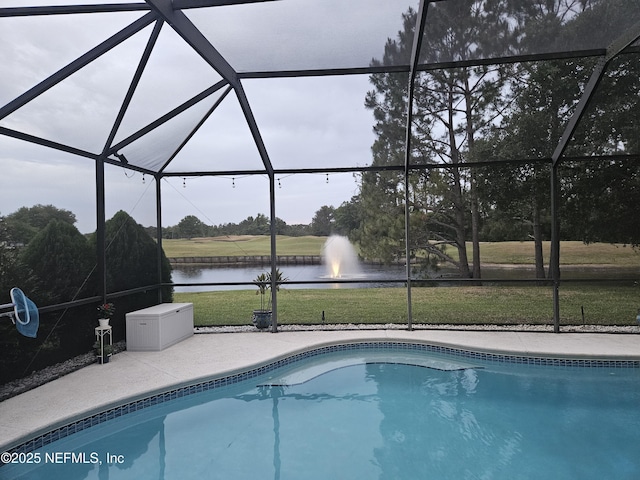 pool with a lawn, a water view, glass enclosure, and a patio area